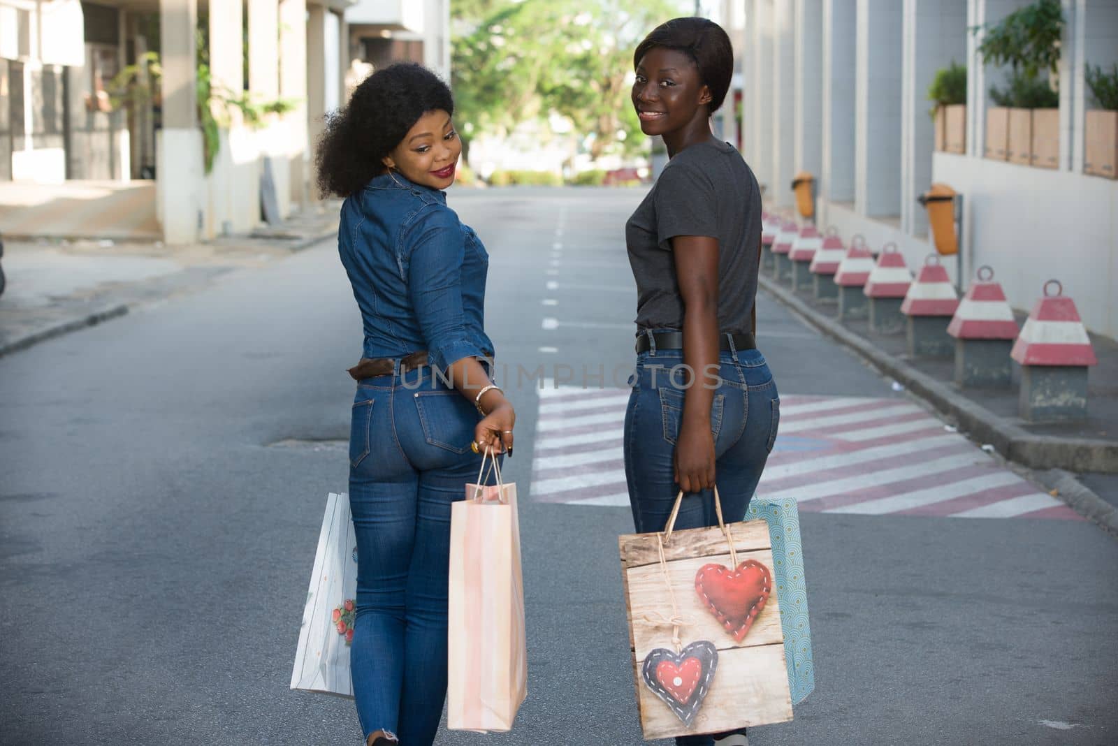 two cheerful girls walking down the street after shopping at the mall
