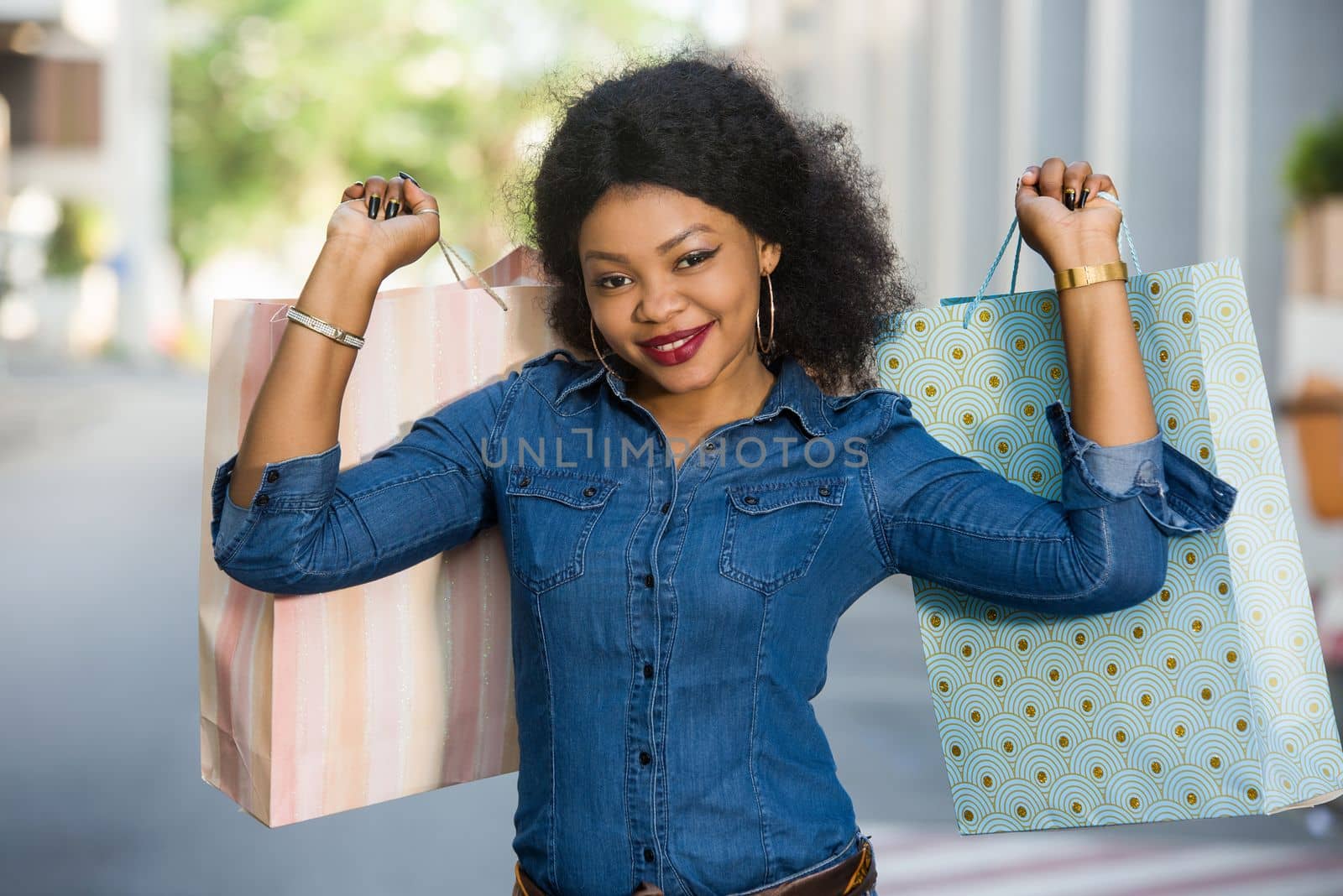 Young cheerful woman holding many colorful shopping bags in the city