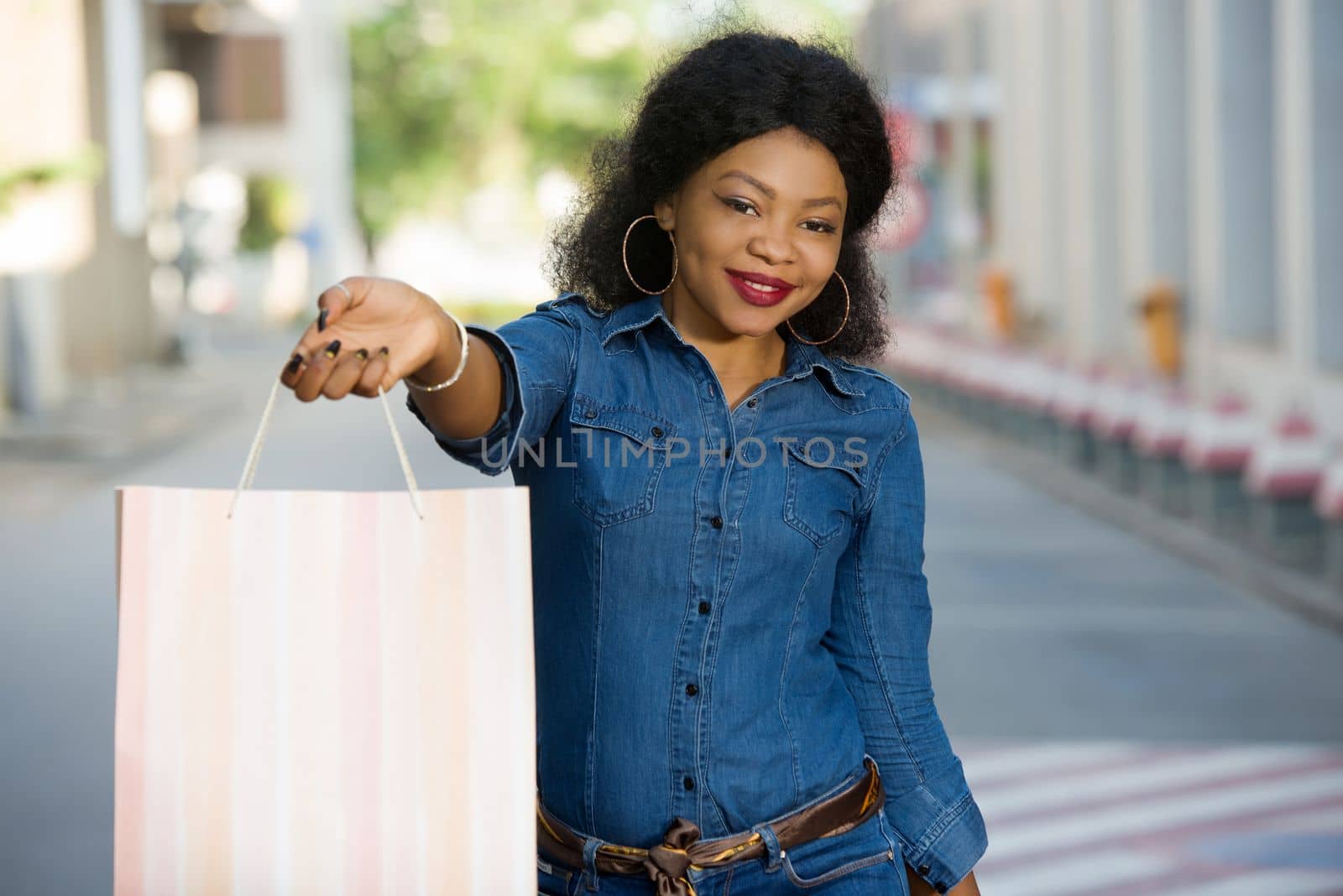 Young cheerful woman holding many colorful shopping bags in the city