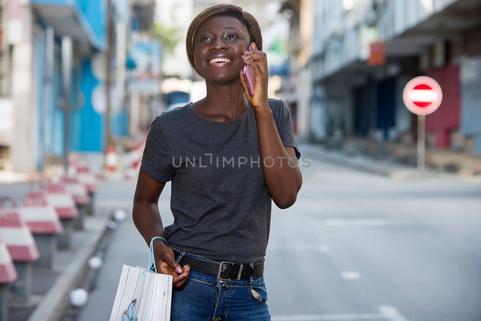 young girl talking on the phone while walking down the street after shopping in the city