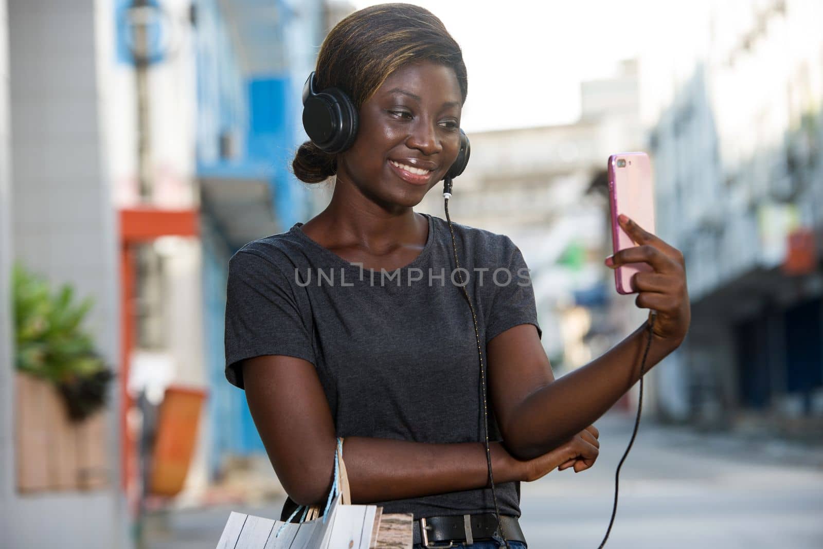 portrait of young stylish girl holding smart phone and shopping bags and shopping in the city