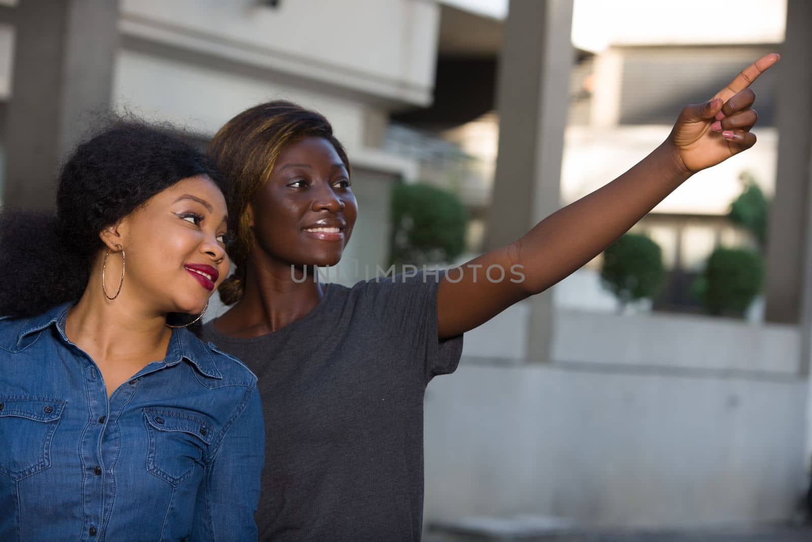 two happy young women holding shopping bags pointing a place with their finger in the city