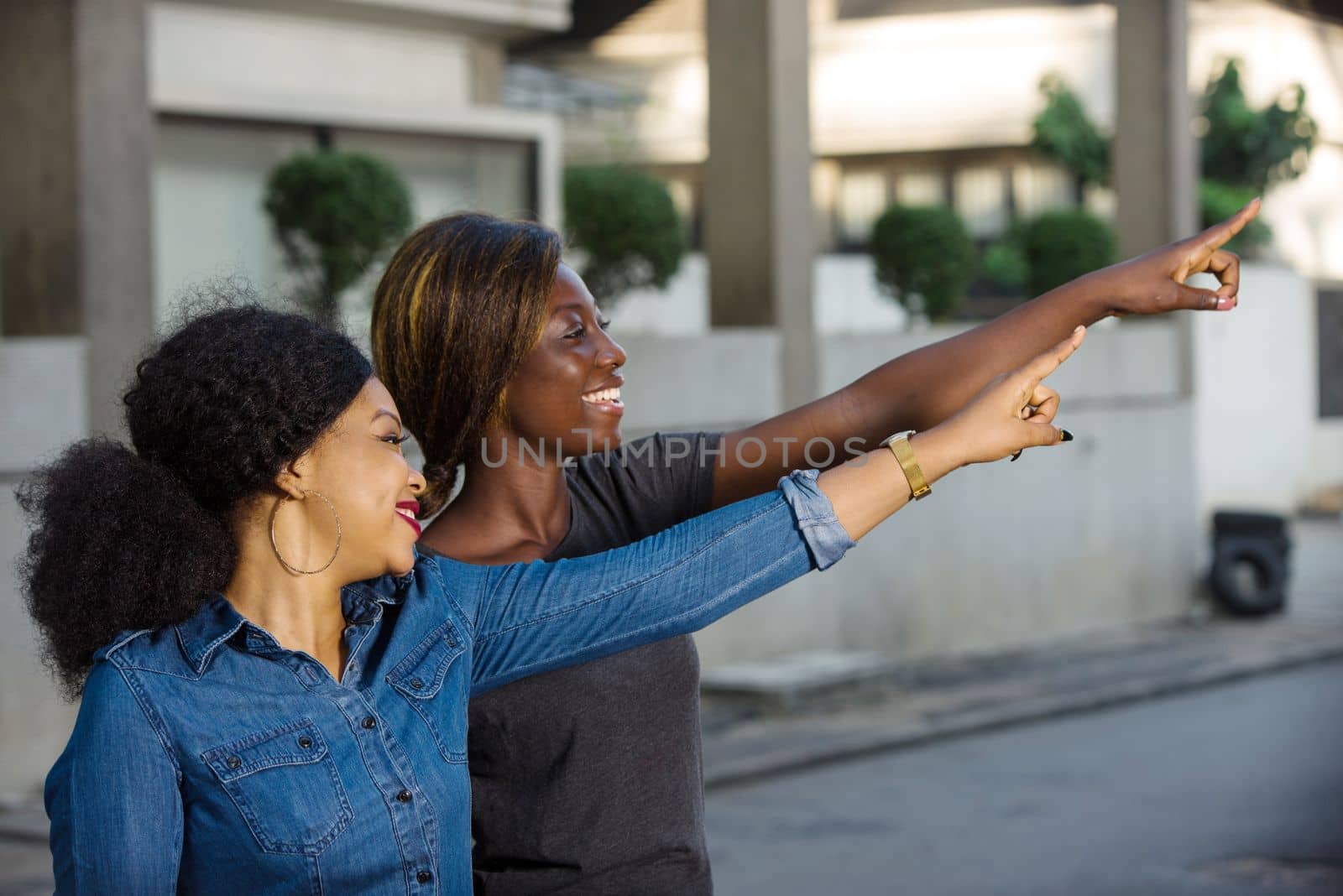 two happy young women holding shopping bags pointing a place with their finger in the city