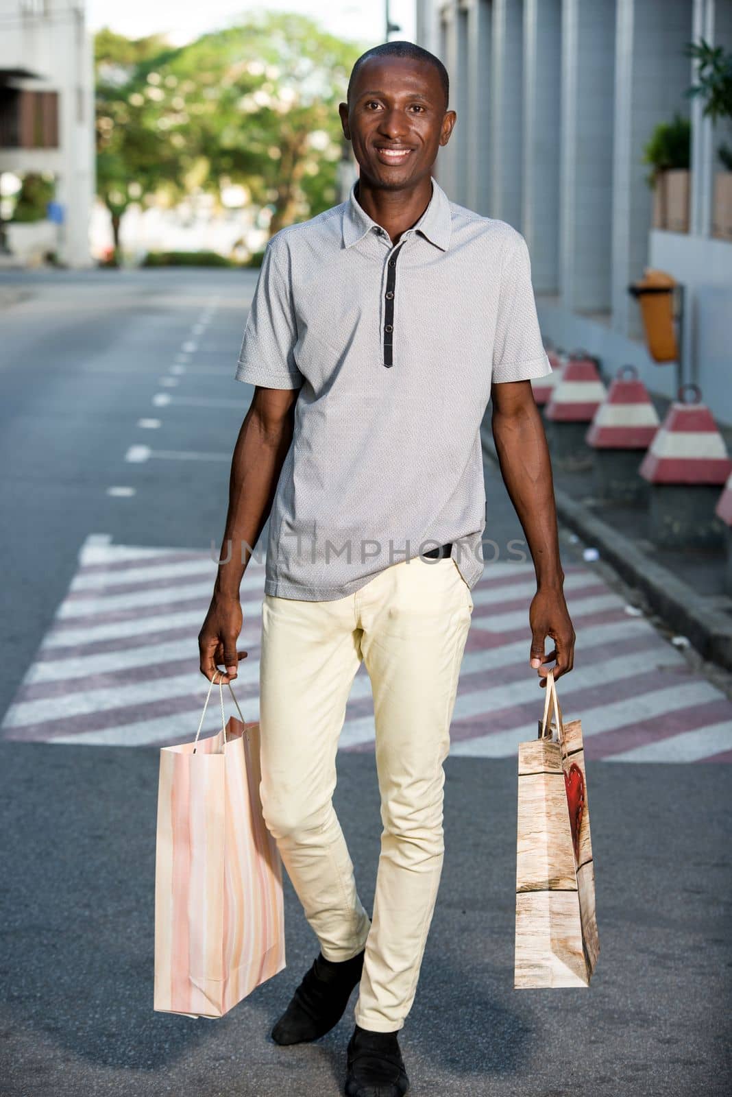 Portrait of happy man with shopping bags walking down the street after shopping in town.