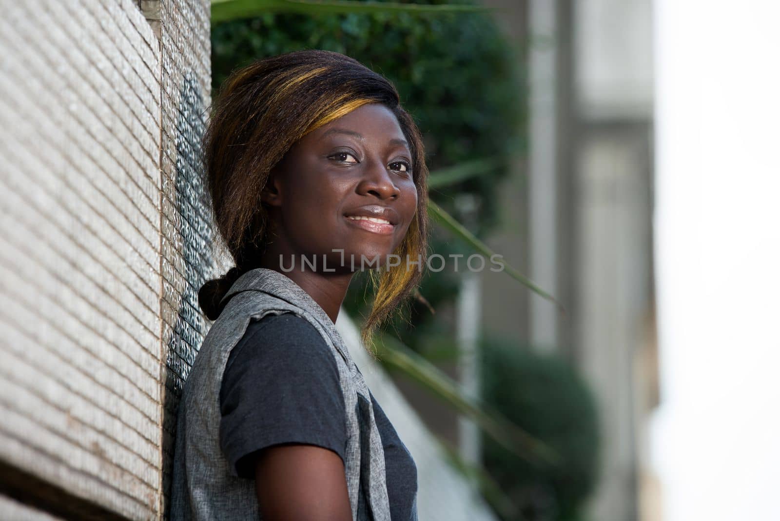 happy woman standing alone against the wall in the street in daylight