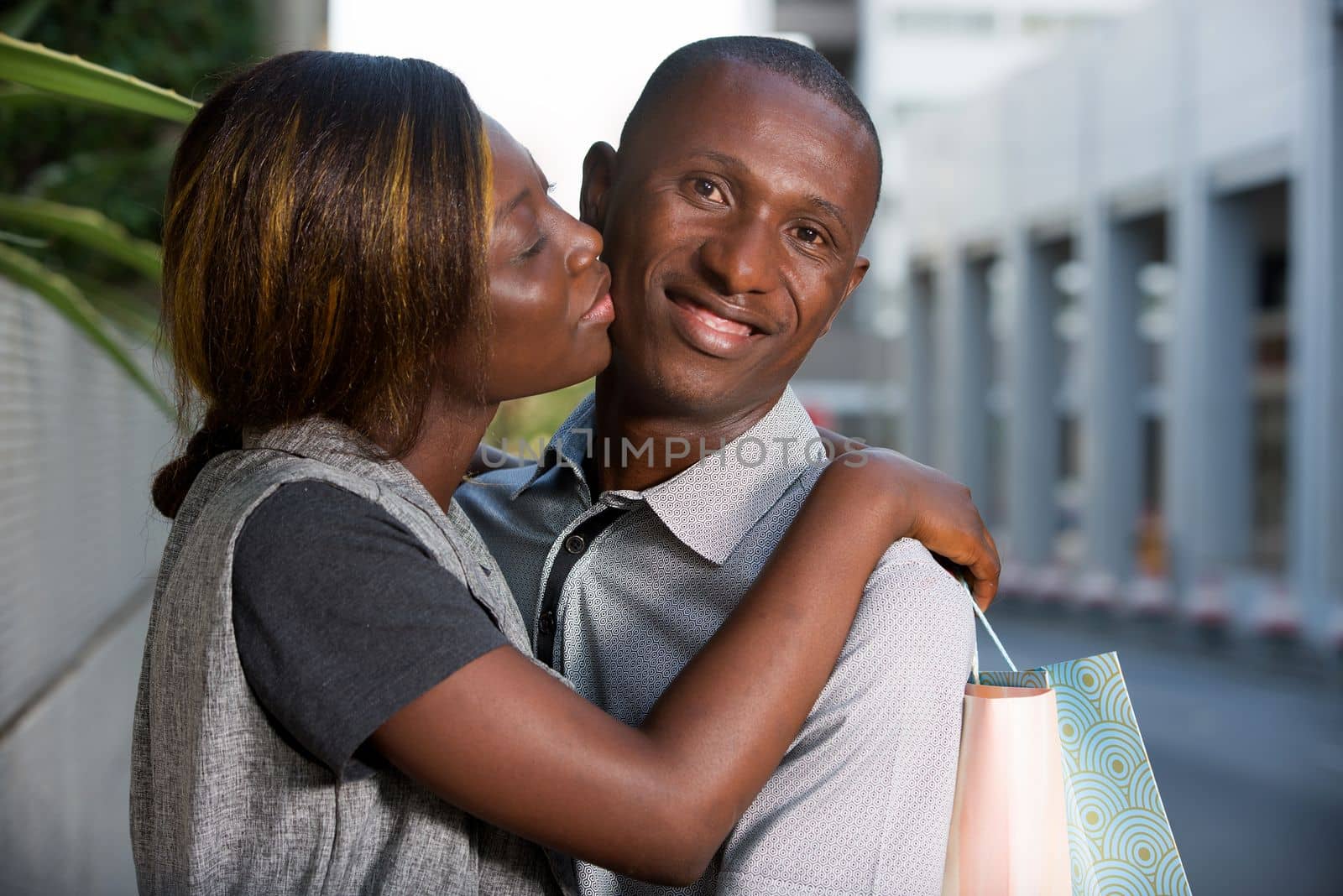 couple doing shopping together .wife happy holding shopping bags and kissing his girlfriend after shopping outside