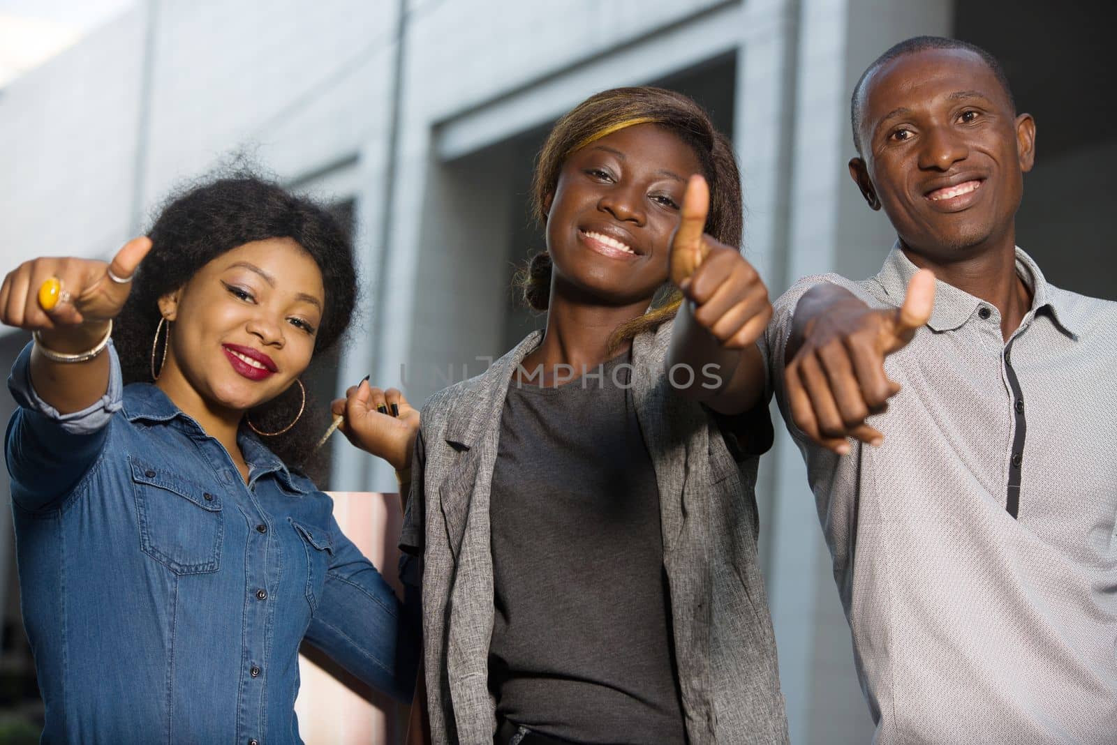 Group of young people happy to shop, holding shopping bags outdoors and having thumbs up.Outdoor shopping group concept.