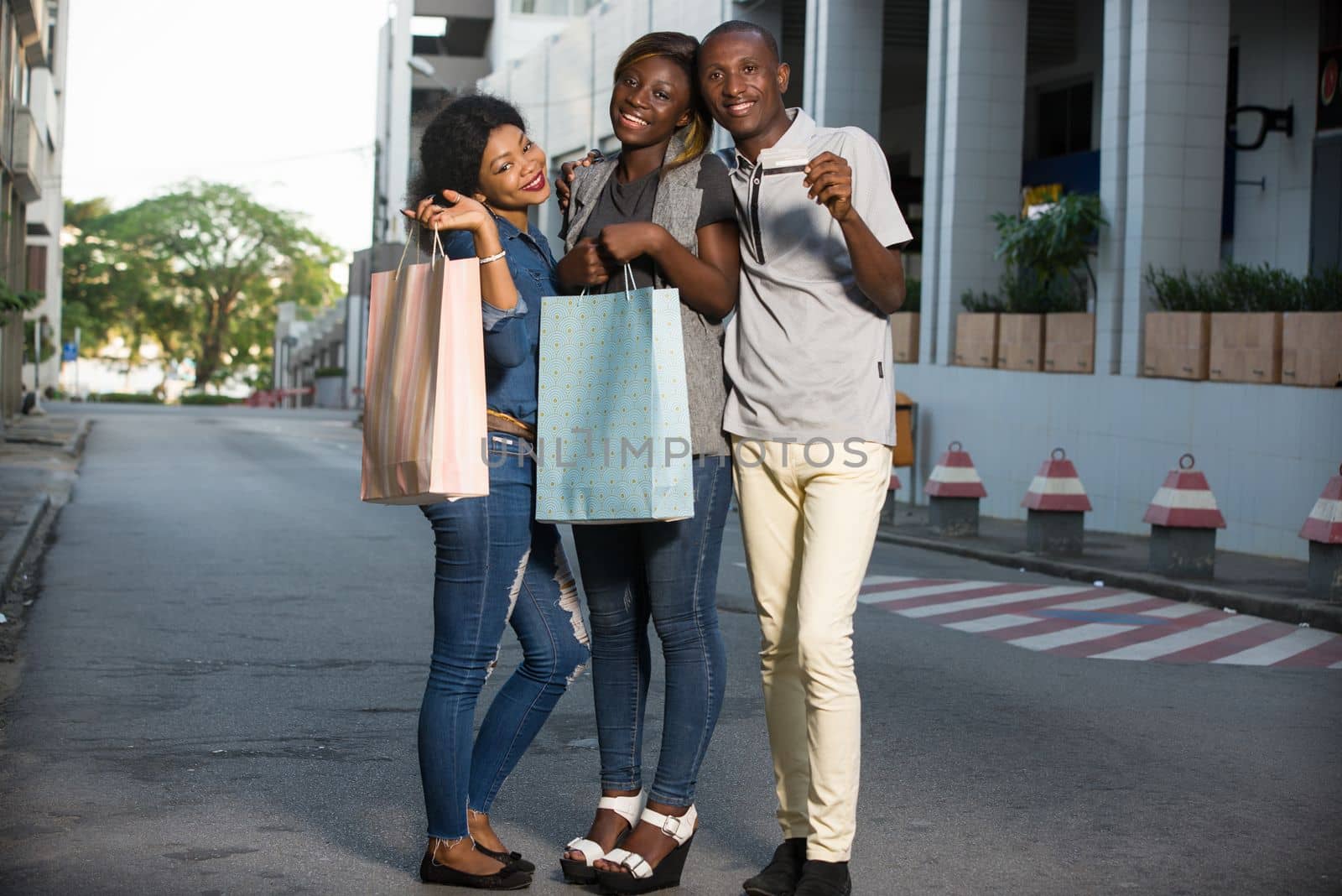 Group of happy young people doing shopping together, holding bags of outdoor shopping and a credit card. Group concept of outdoor shopping.