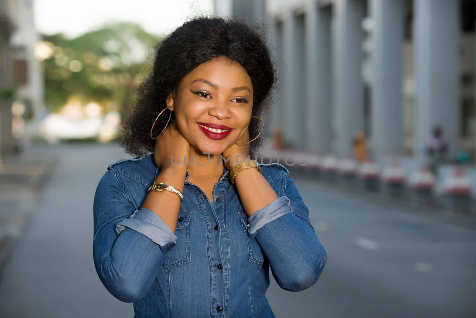 Young happy and free woman standing in the street laying hands on the neck and looking at the camera