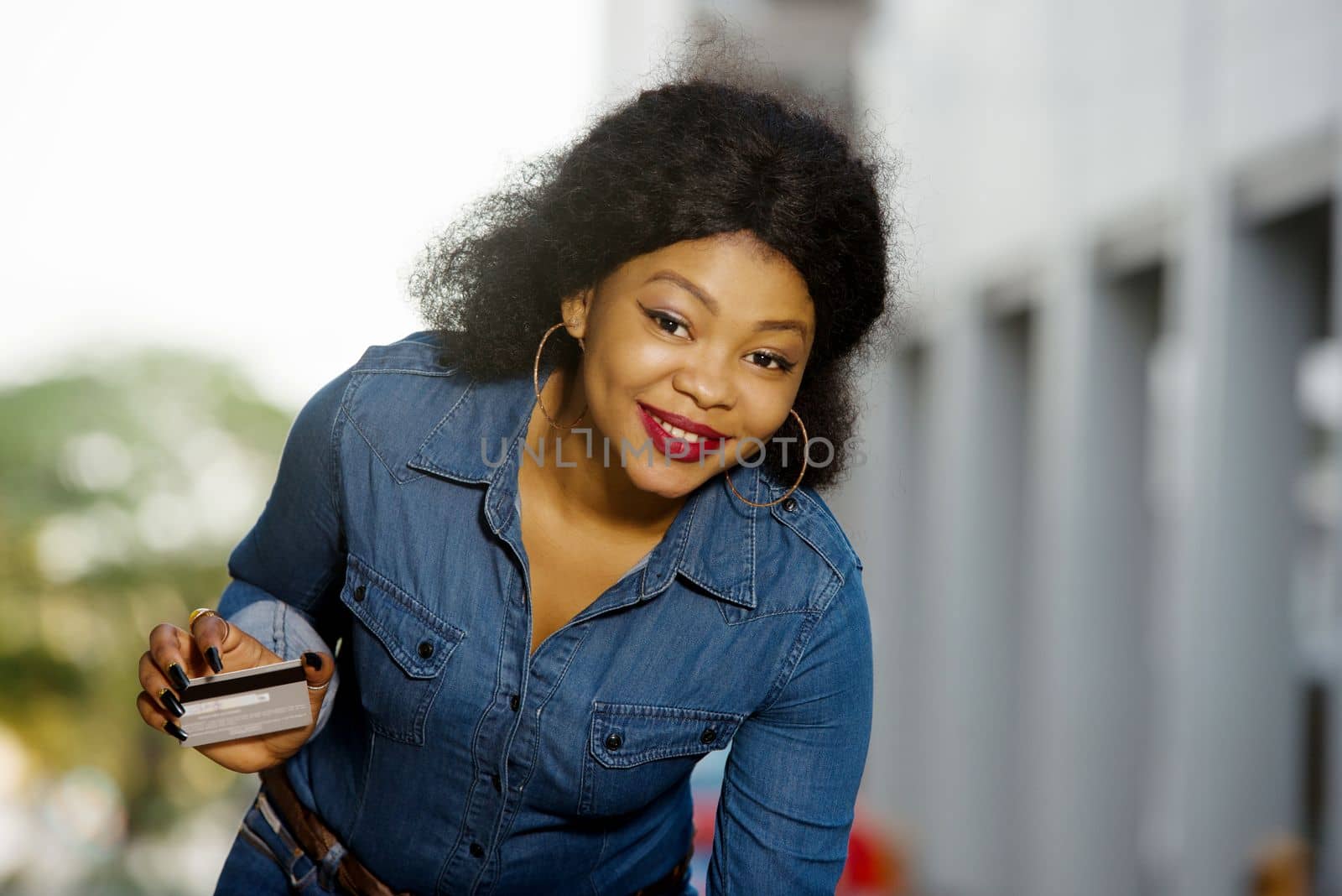 Portrait of smiling woman with a credit card in a hand in the city