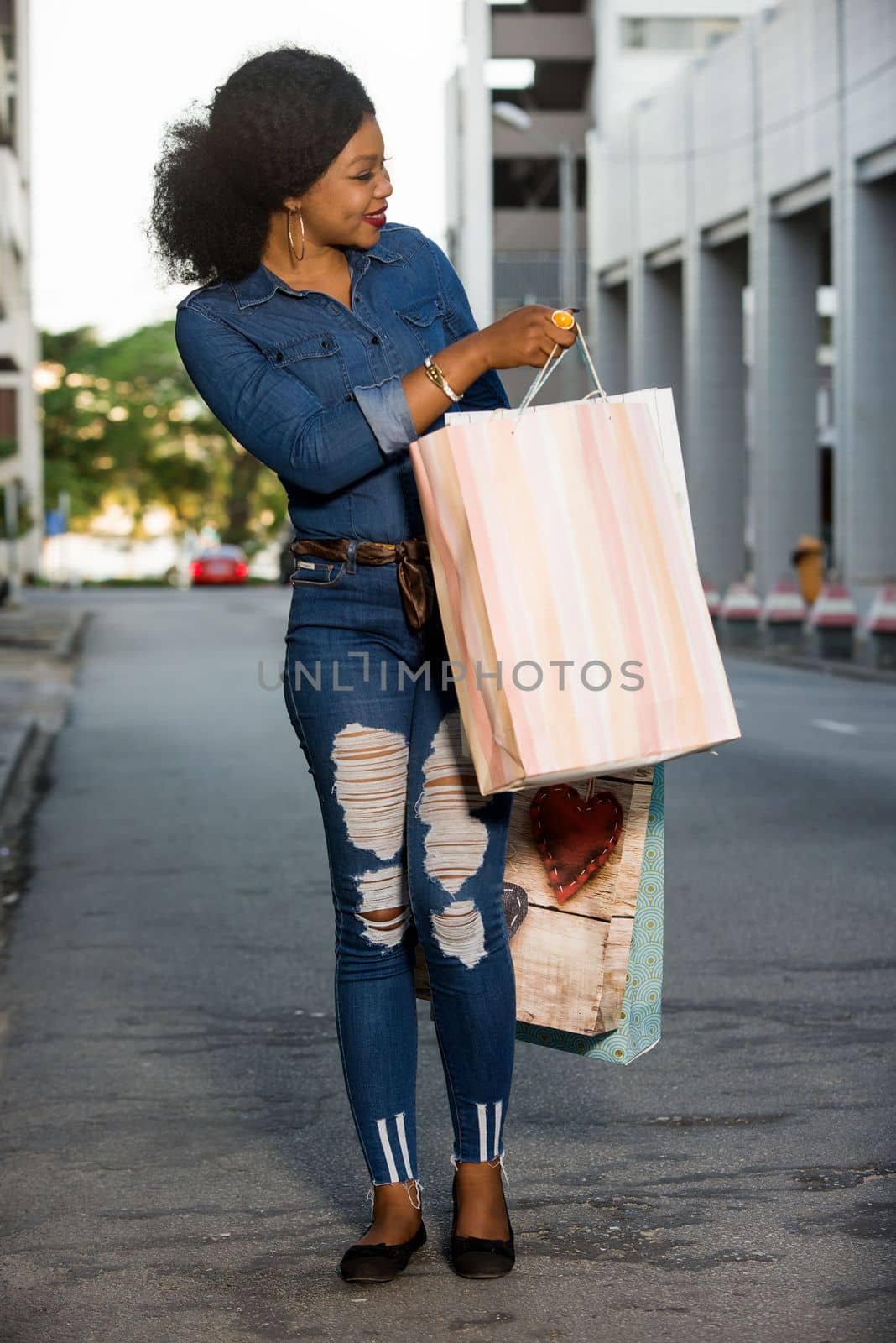 Girl standing in the street after shopping with shopping bags smiling.