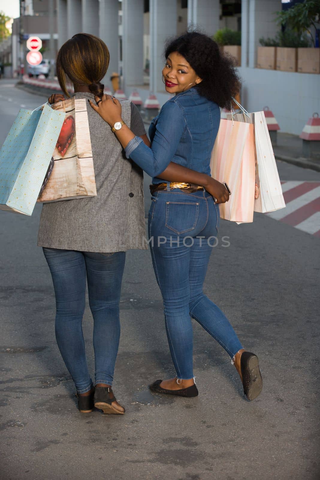 Young girls walking down the street after shopping with shopping bags smiling.