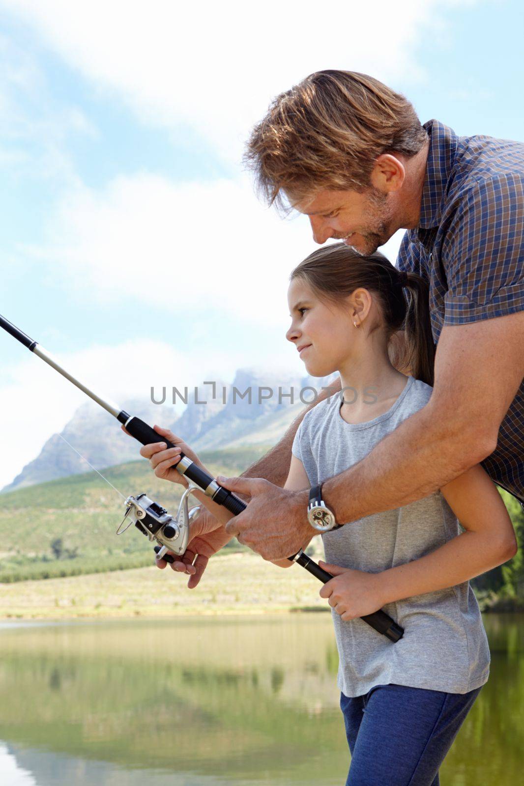 Weve got one. a father showing his daughter how to fish outdoors