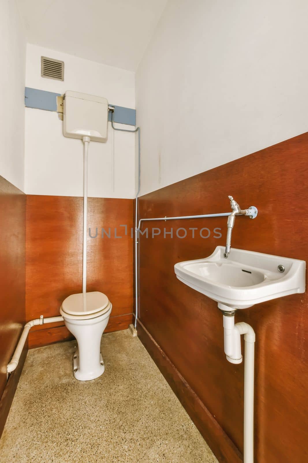 a toilet and sink in a small bathroom with wood paneling on the walls behind it is a wall mounted air condition