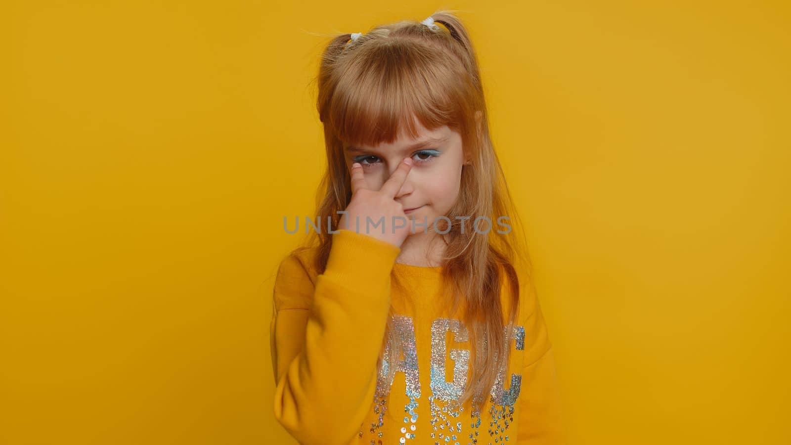 I am watching you. Young preteen child girl kid pointing at her eyes and camera, show I am watching you gesture, spying on someone, see. Female little toddler children isolated on yellow background