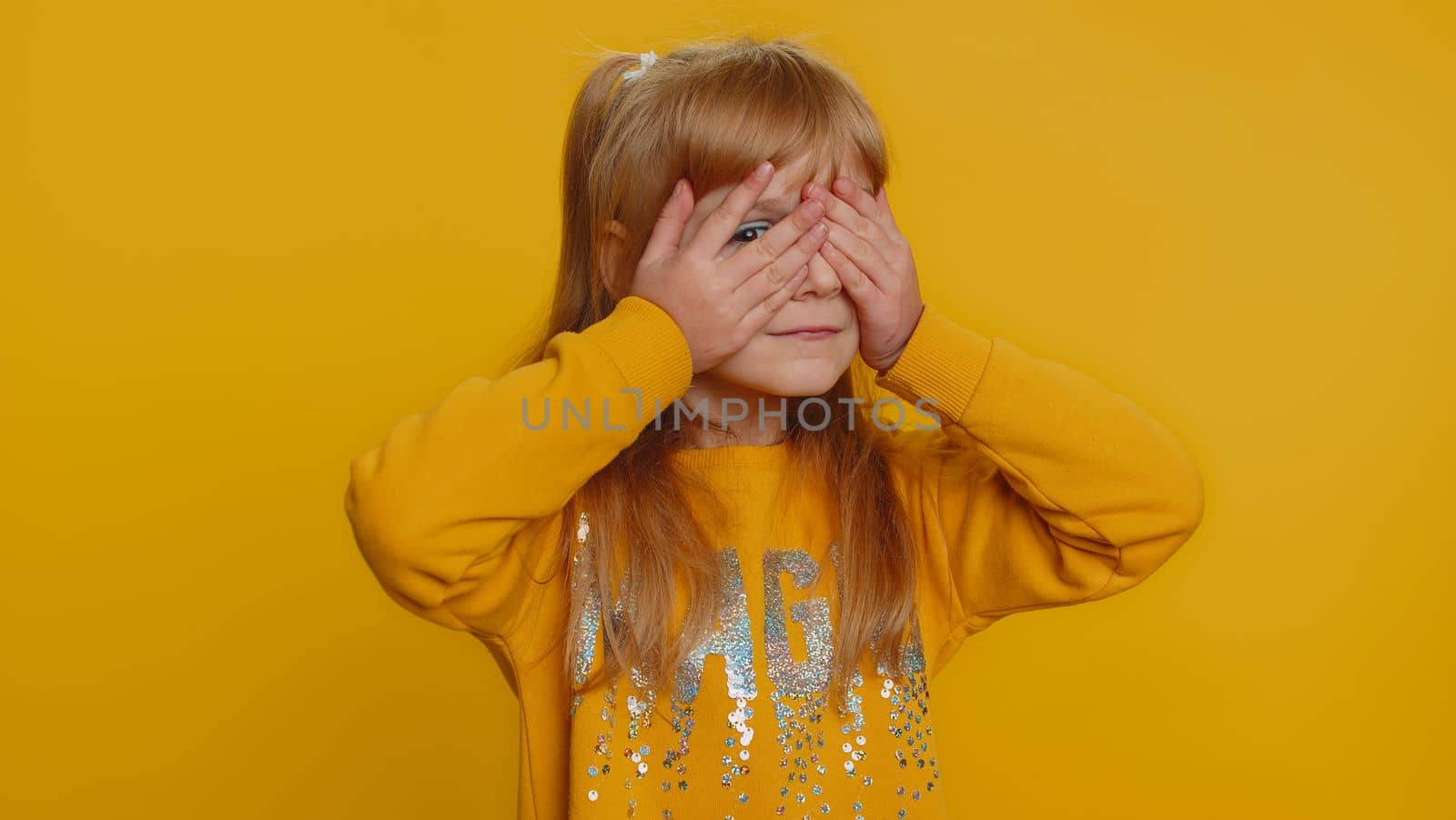 Dont want to look at this, awful. Young preteen child girl kid closing eyes with hand showing stop gesture, confused shy scared to watch. Little toddler children isolated alone on yellow background