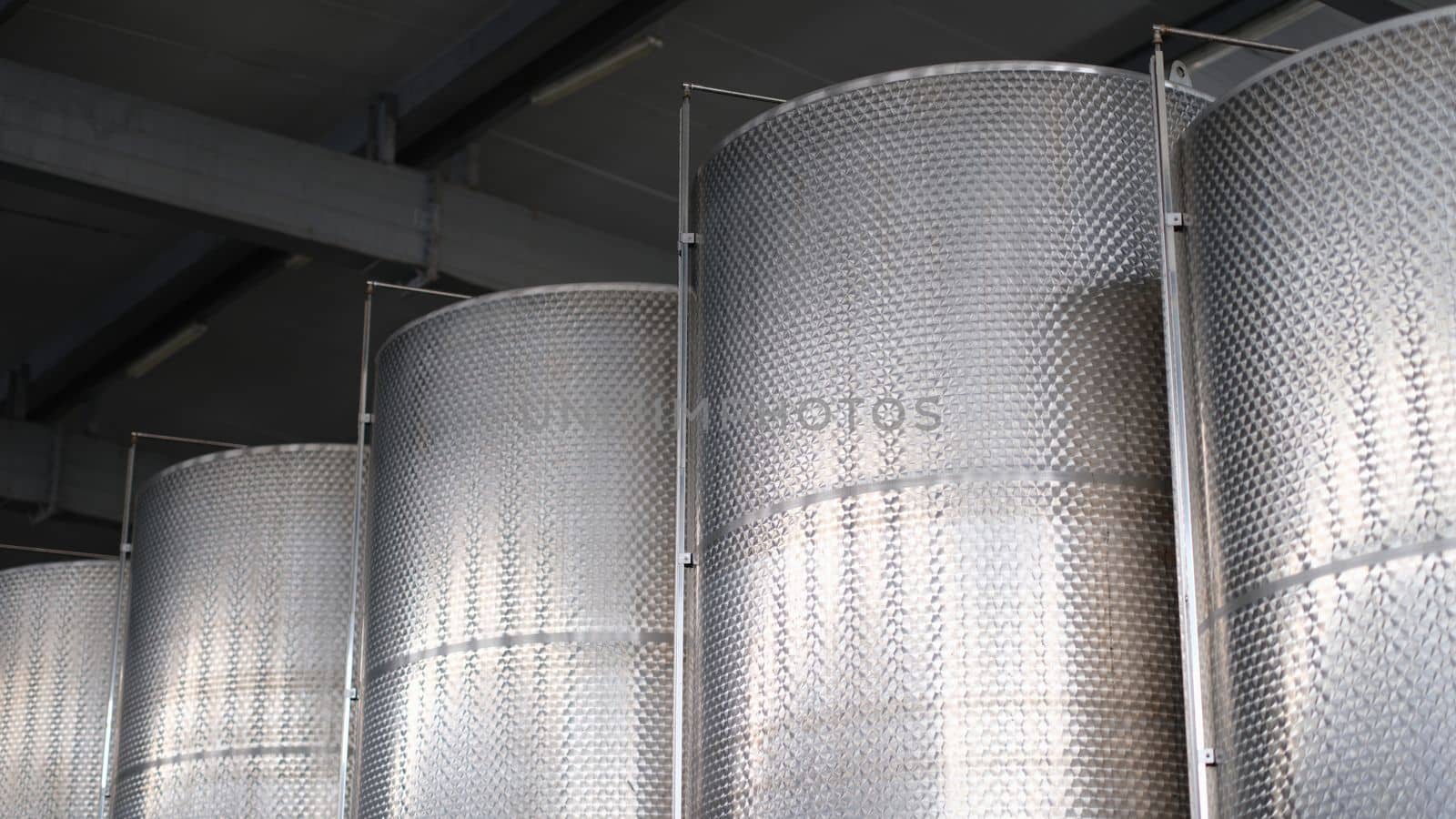 Steel tanks for storing alcohol in winery closeup. Modern brewery with brew kettles pipes and stainless steel tanks.