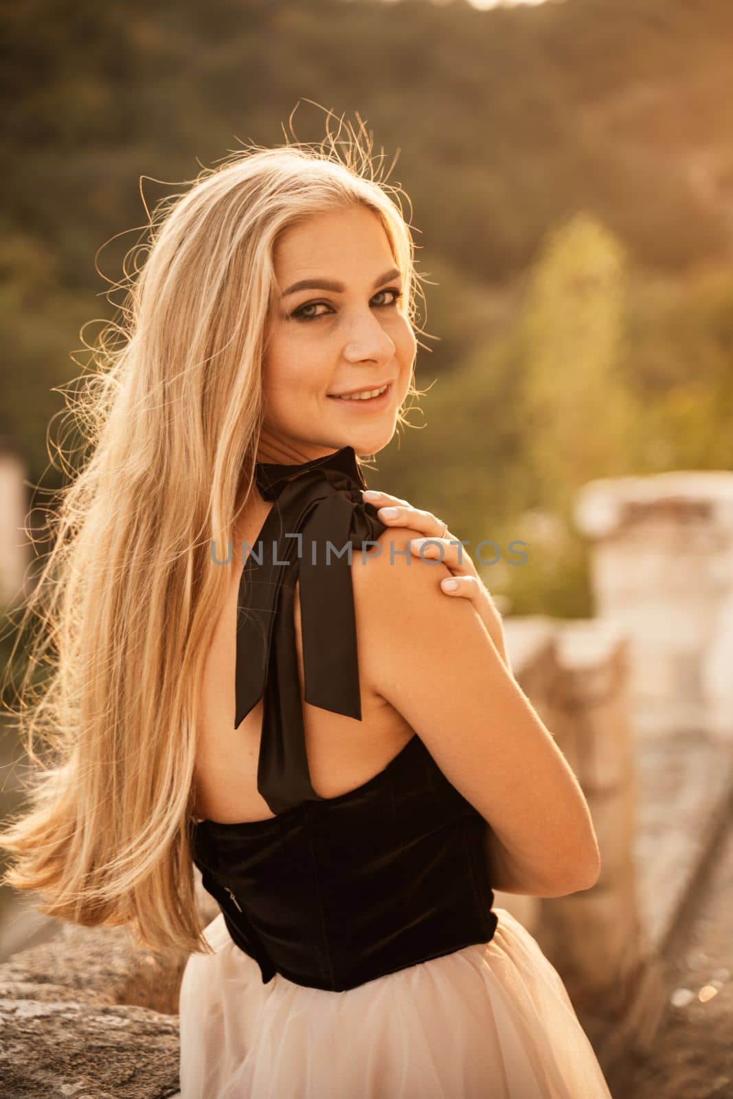 Blonde long hair, nature summer happy adult girl with long blond hair developing in the wind in nature. Dressed in a black top, white skirt