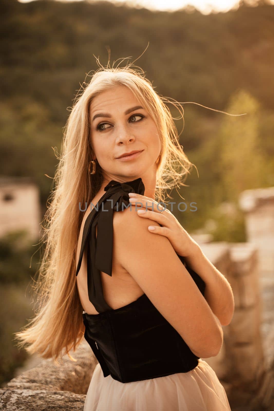 Blonde long hair, nature summer happy adult girl with long blond hair developing in the wind in nature. Dressed in a black top, white skirt