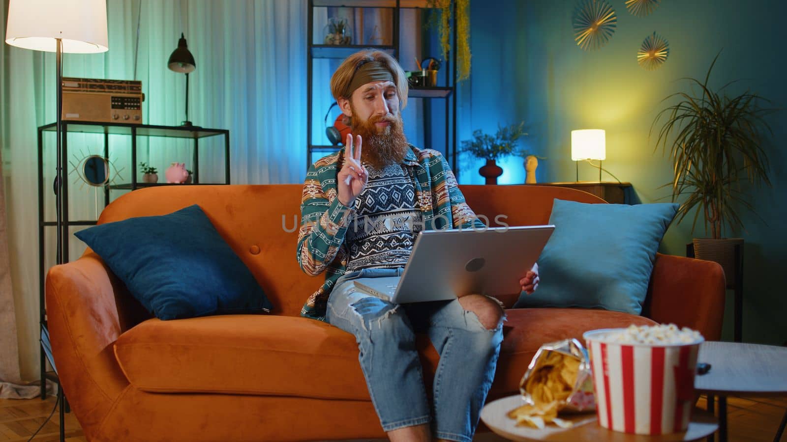 Man sitting on home couch, looking at camera, making video conference call with friends or family by efuror