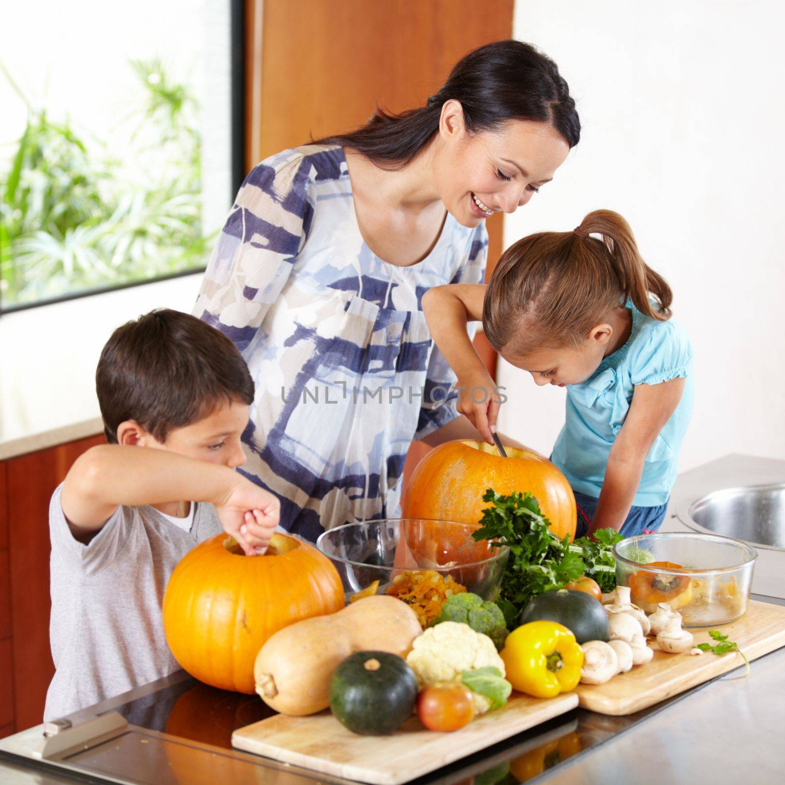 I think its ready. a mother helping her children carve pumpkins for halloween