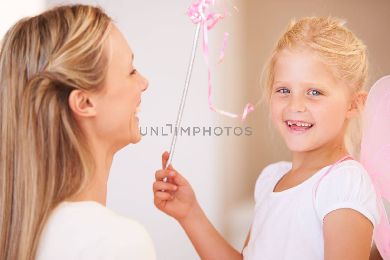 Shell grant her mum any wish she wants. Portrait of a smiling girl dressed up as a fairy and holding a wand standing infront of her mother