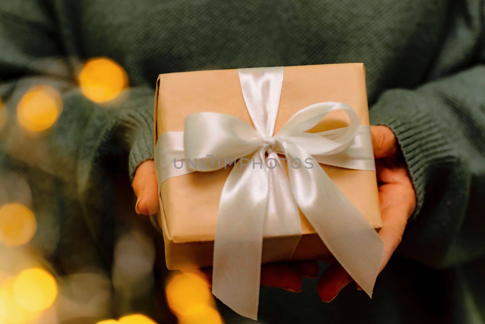 Female hands hold a craft gift box. Christmas, birthday concept. Festive background with bokeh