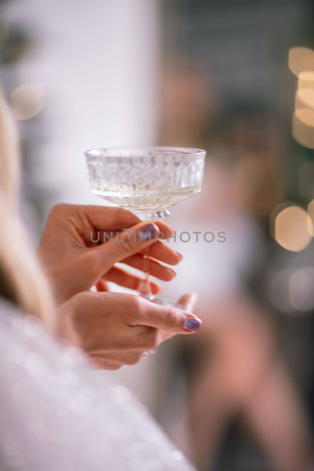 The hands of a woman hold a glass of champagne on a background of golden beke. The concept of the holiday, Christmas, new year, birthday. by Matiunina