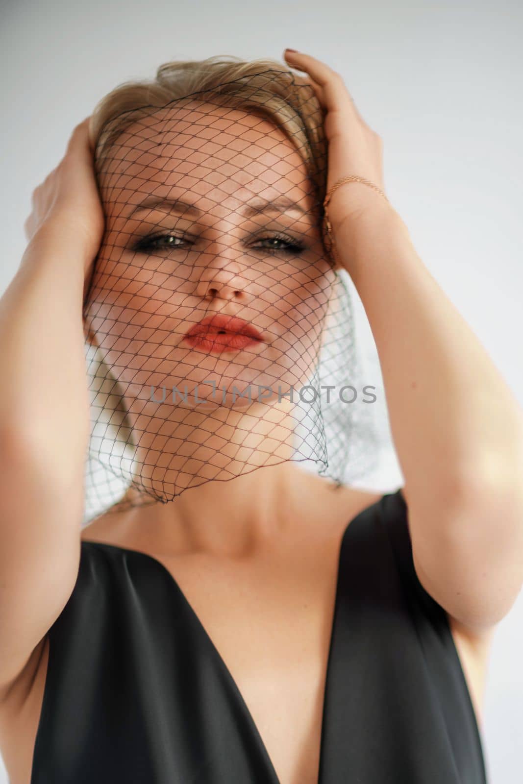 Portrait of a beautiful blonde woman with a veil in a black dress.