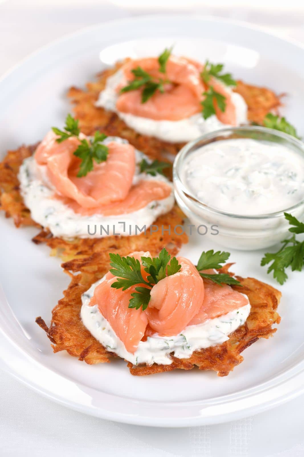 Crispy Potato fritters (a pancake, especially one made with grated potato) with cream cheese sauce with herbs and salmon