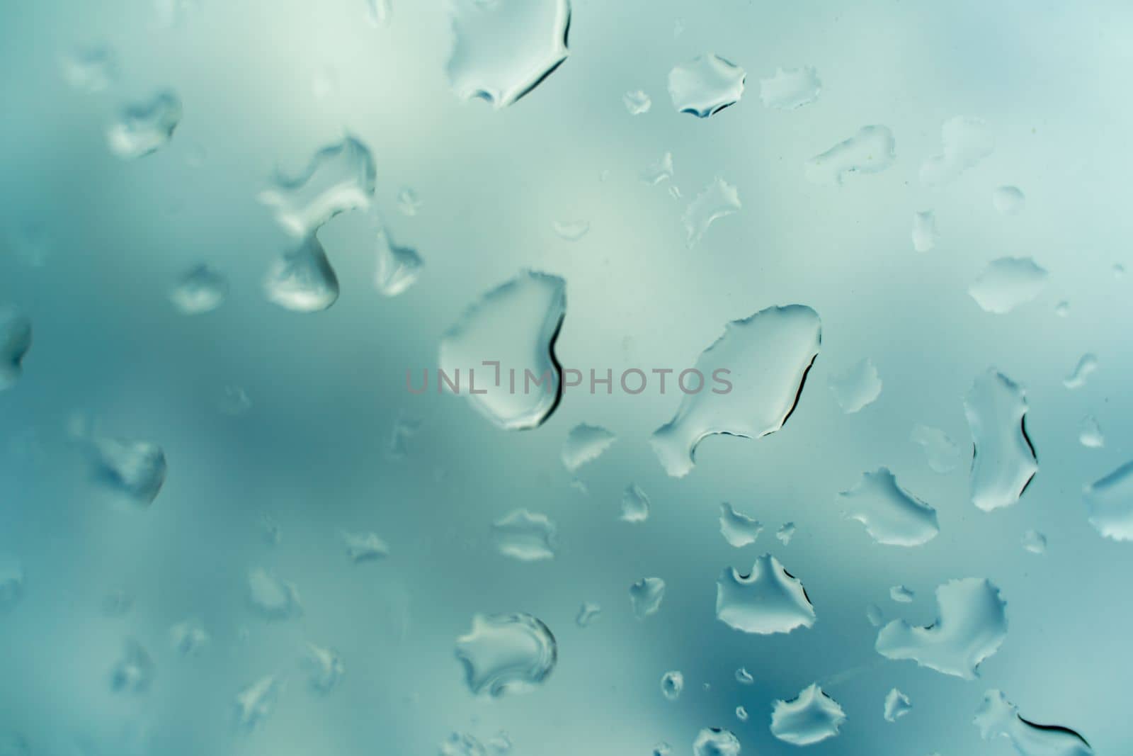 Raindrops on glass against blue sky. Window view background screensaver. Place for text banner.