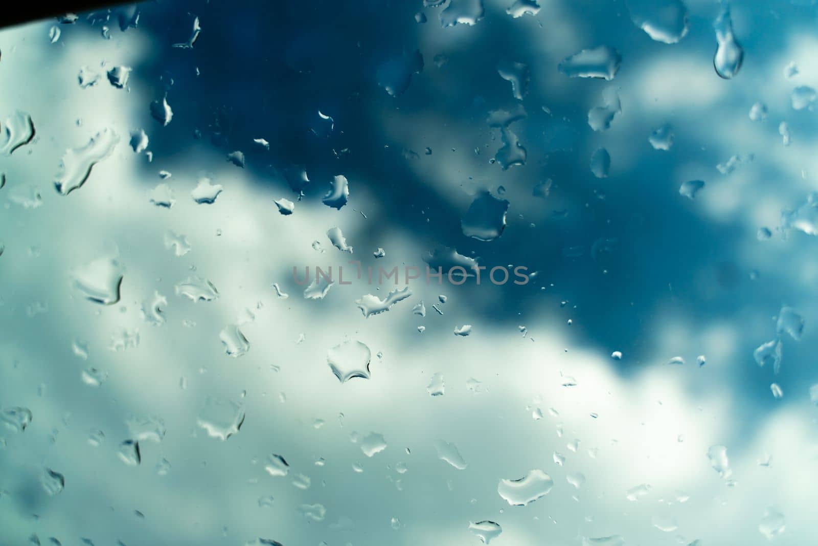 Raindrops on glass against blue sky. Window view background screensaver. Place for text banner.
