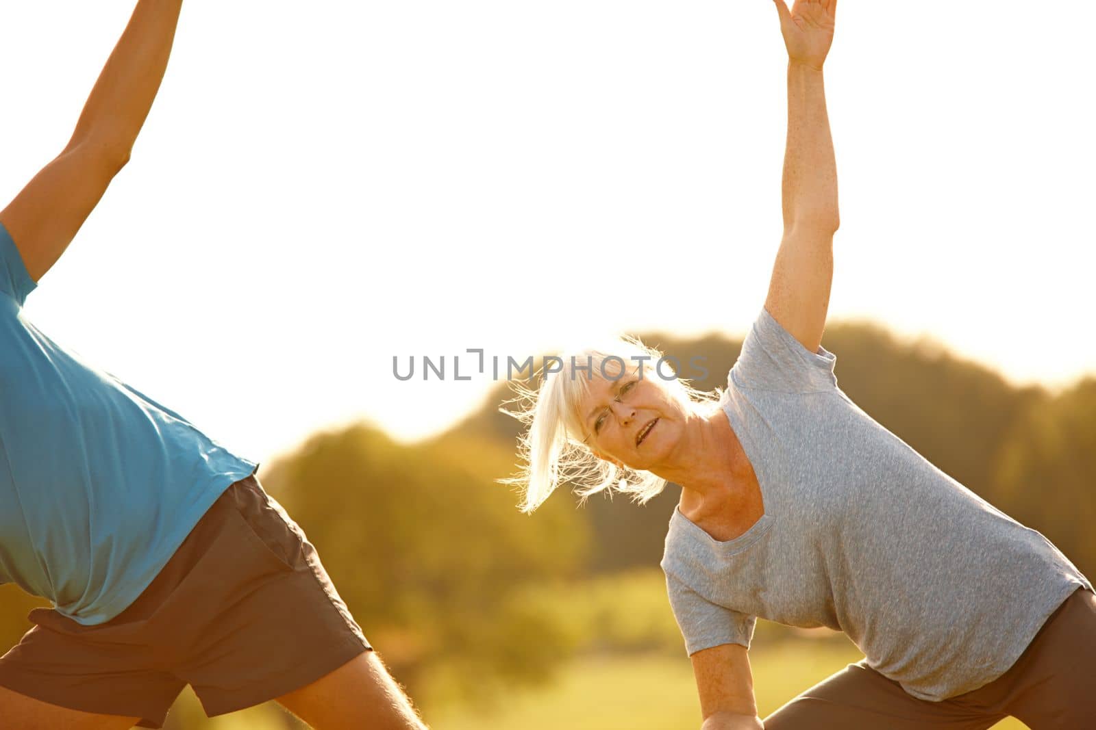 Staying flexible. a mature couple doing yoga together outdoors