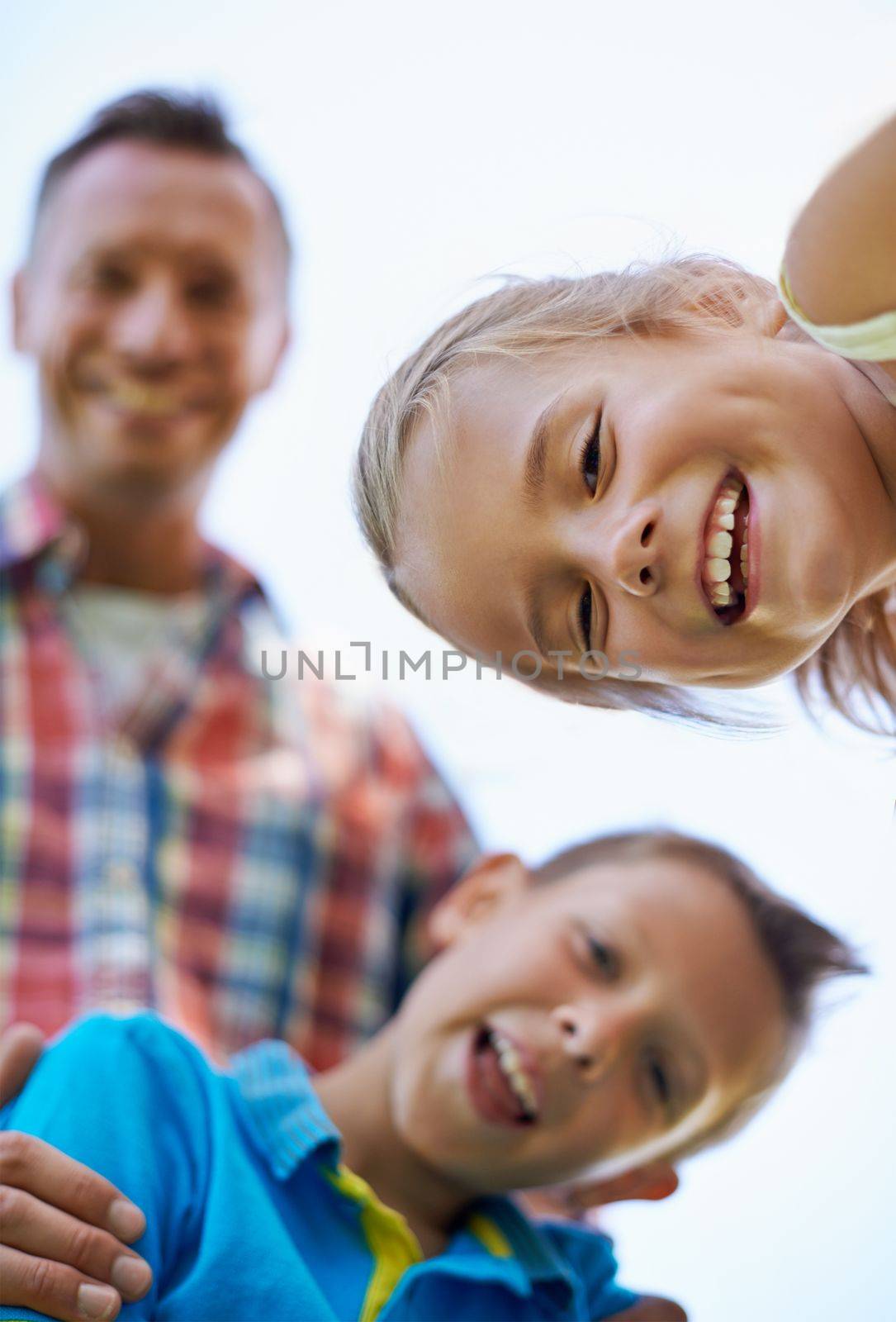 An awesome day with dad. A low angle portrait of a happy two happy kids and their dad spending the day outdoors