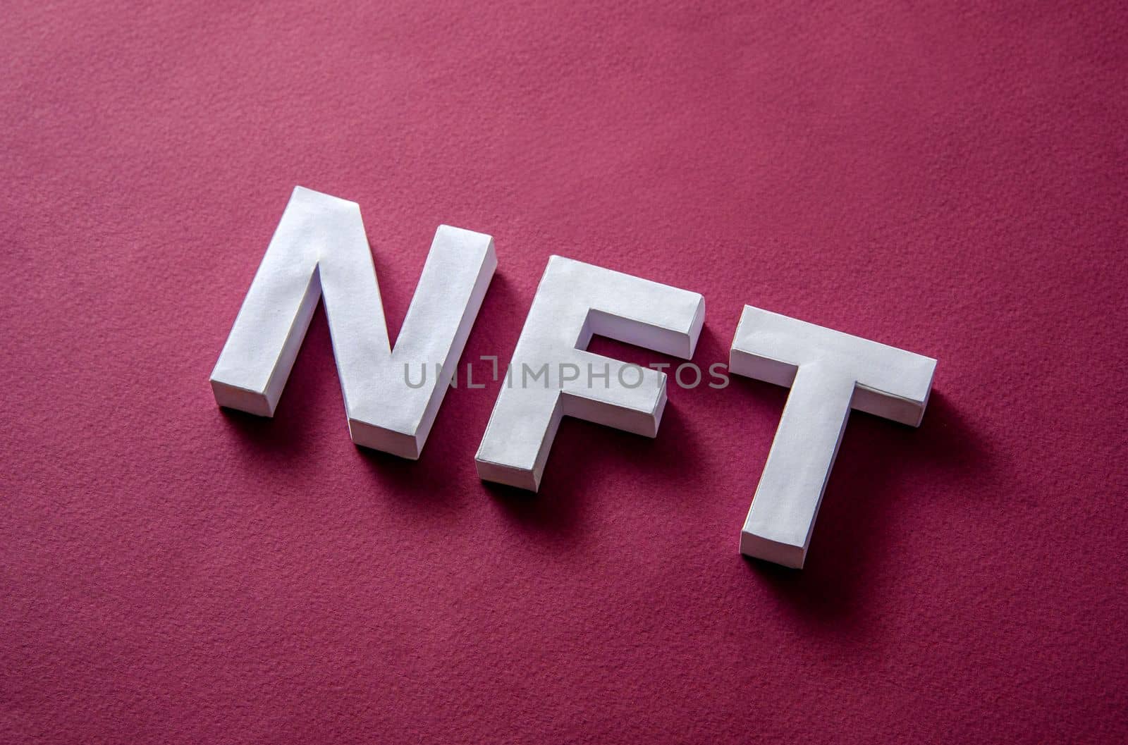 NFT text on a red background diagonally as a concept of modern technologies of online payments and cryptocurrency in a marketplace or auction for digital property for collector. High quality photo