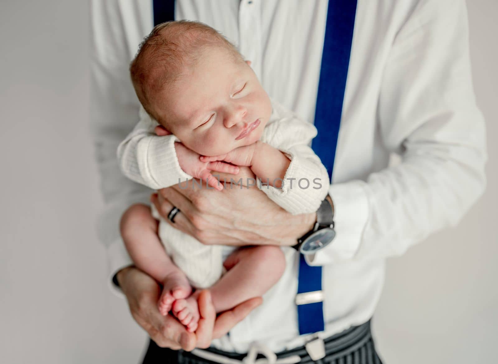 Father holding sleeping newborn baby boy.