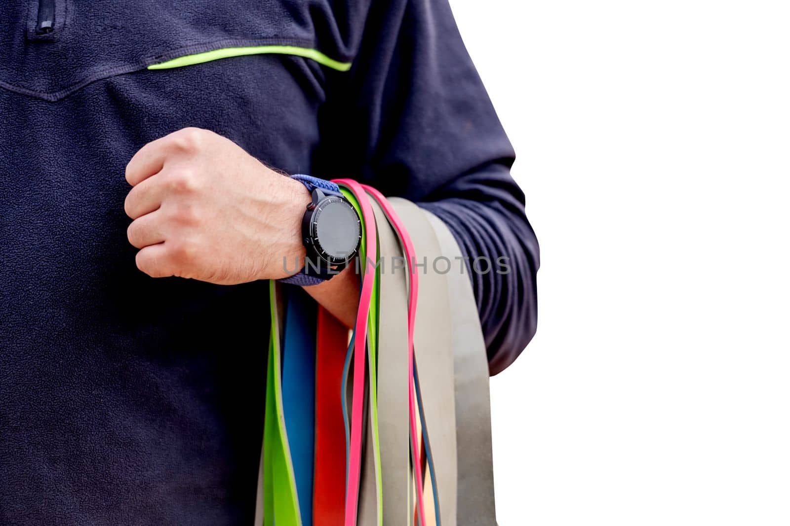 Strong man guy holding set of colorful elastic rubber bands at the stadium outdoors. Athlete male person during workout with additional sport equipmant