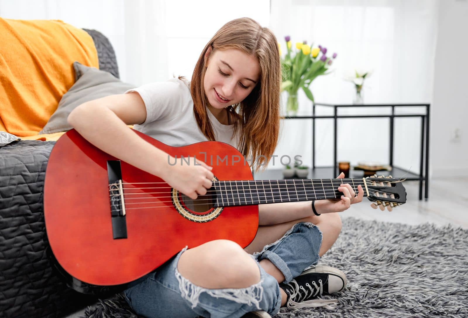 Girl teenager practicing guitar playing at home sitting on floor. Pretty guitarist with musician instrument