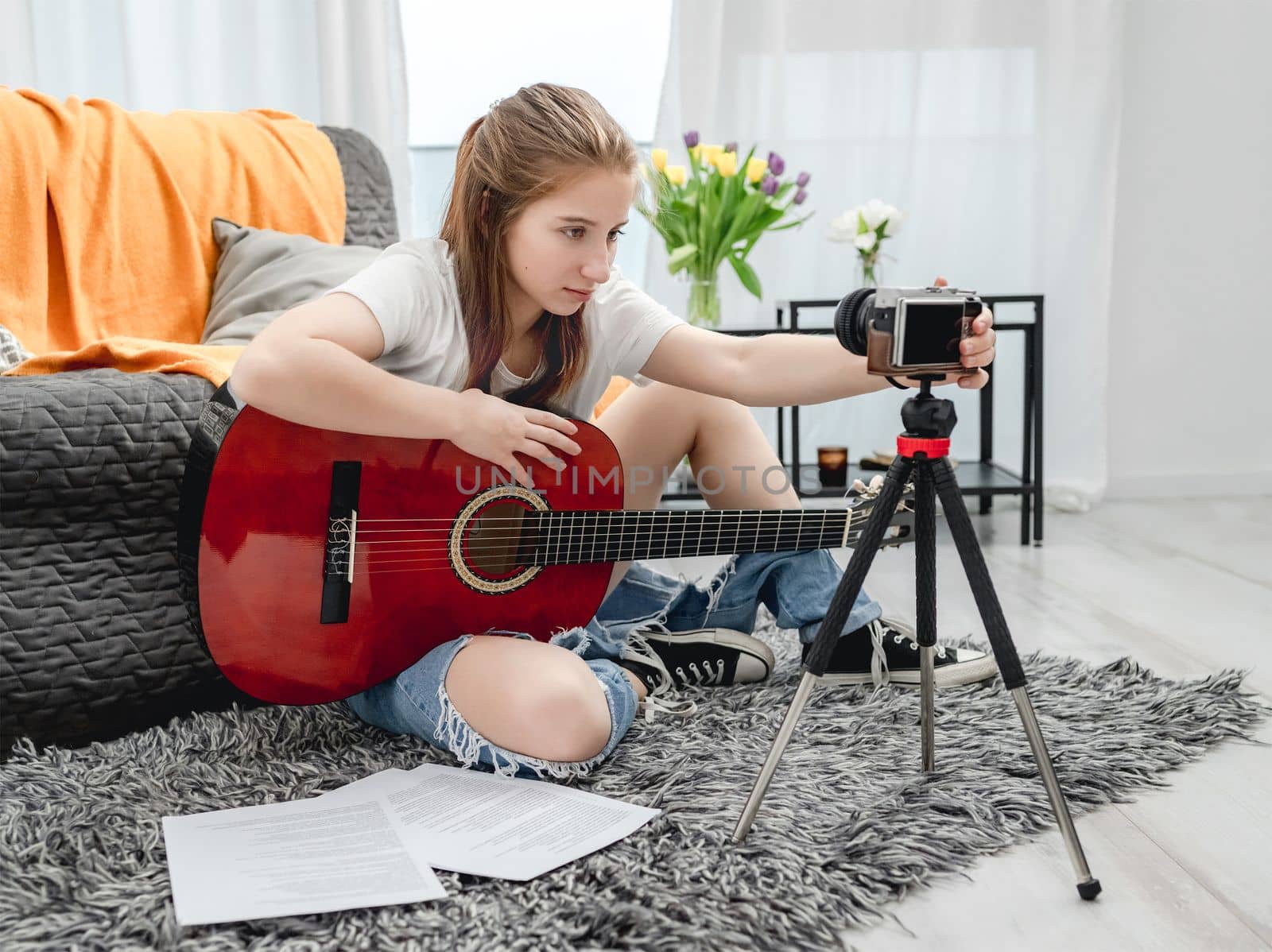 Girl teenager with guitar recording streaning online lesson with camera for blog followers in social media. Young musician guitarist filming vlog