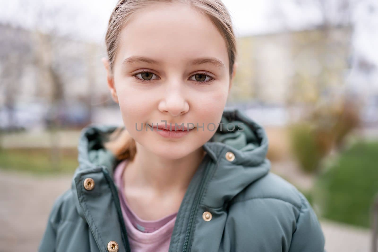 Preteen girl street portrait in city with blurred background. Cute female child kid outdoors at autumn time