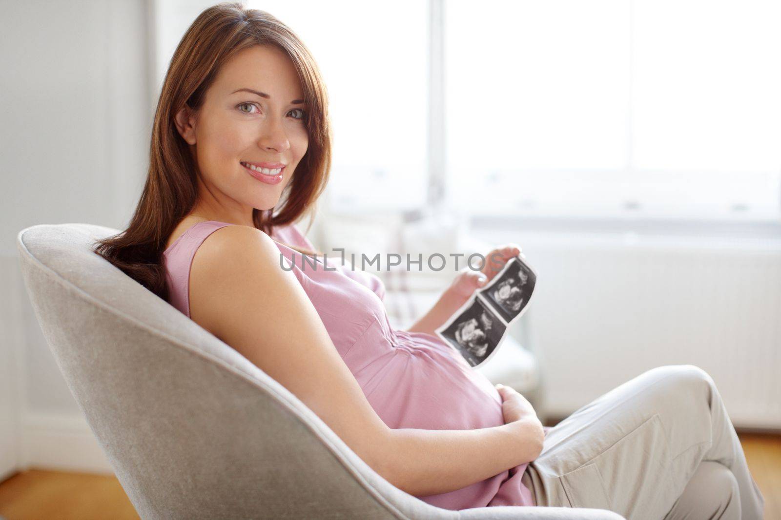 Everything is looking good. Portrait of a pretty young woman looking at her babies sonogram while sitting at home