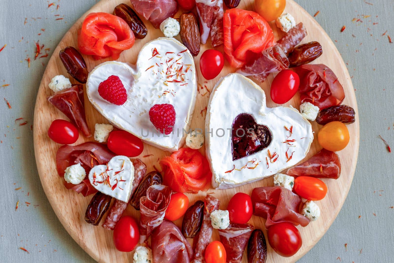 cheese plate with heart shape cheese, fruits and delicatessen, decorated with edible flowers