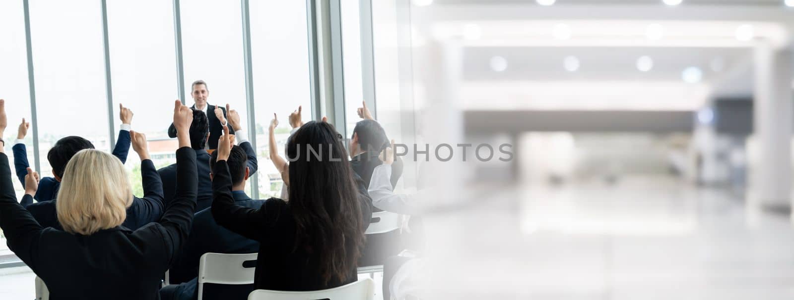 Group of business people meeting in a seminar conference widen view . Audience listening to instructor in employee education training session . Office worker community summit forum with speaker .