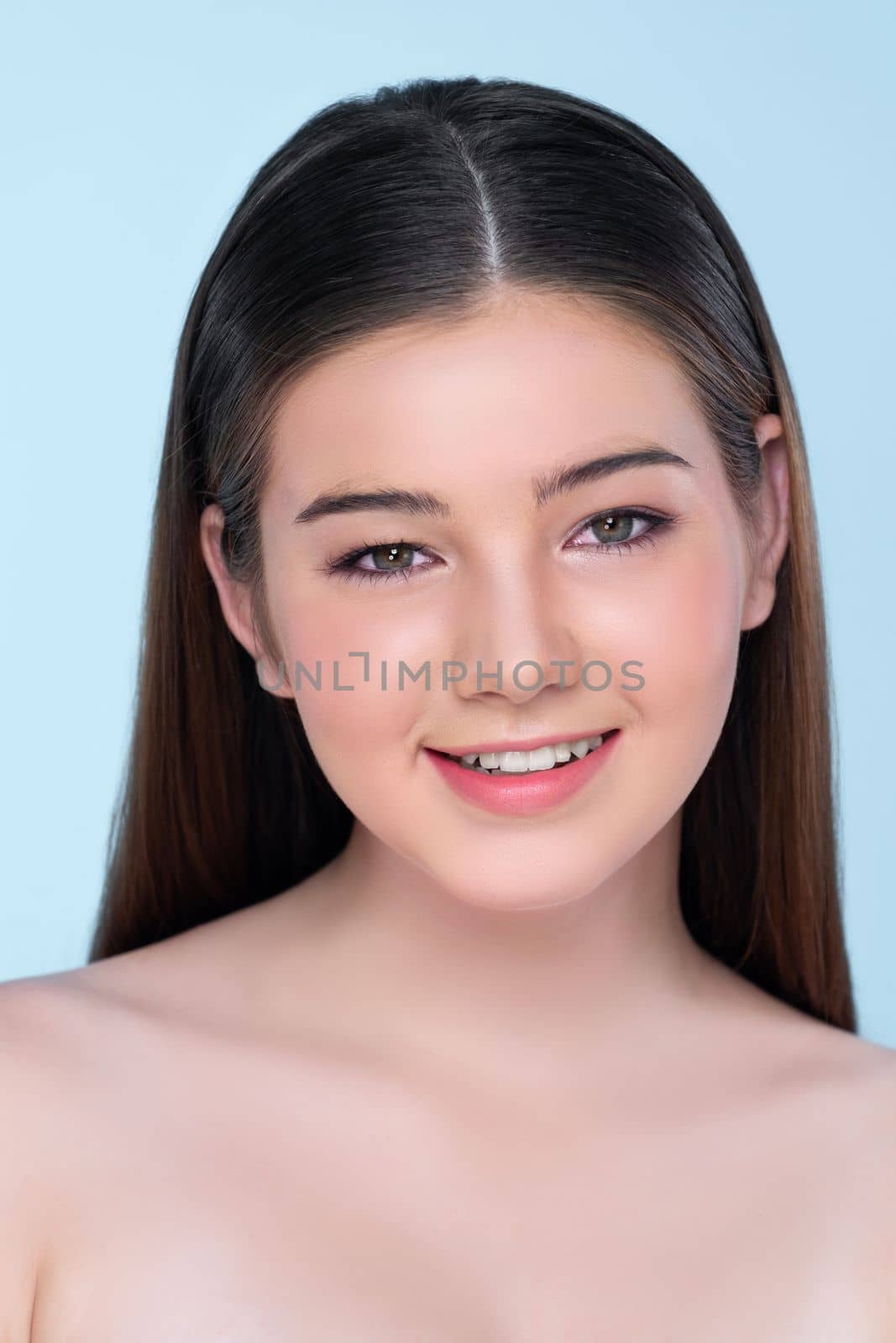 Natural beauty closeup portrait of young charming brunette girl looking at camera. Perfect smooth face skin attractive young girl with bare shoulder for skincare and cosmetic product.