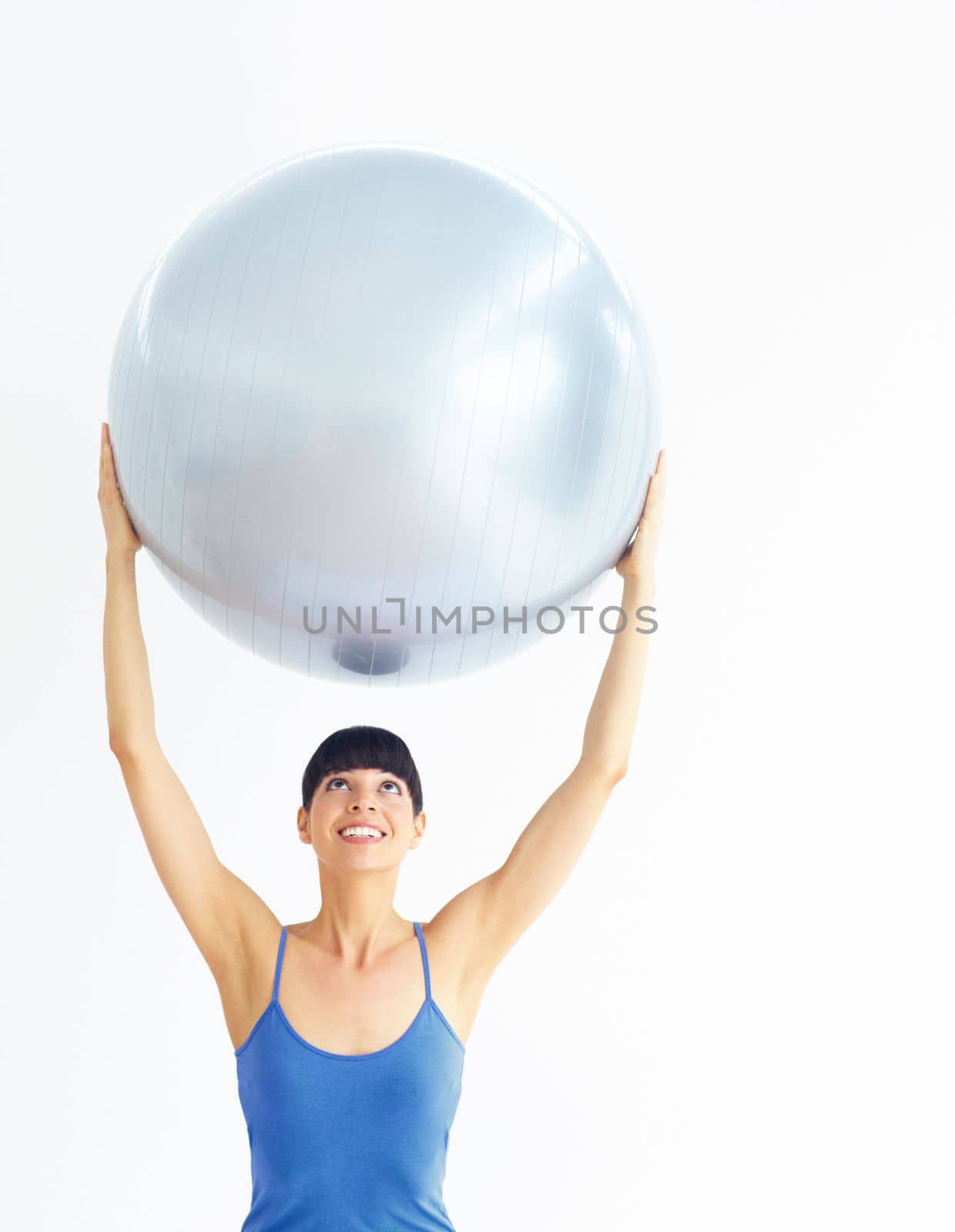 Holding up great health ideals. Healthy young woman exercising while holding an exercise ball