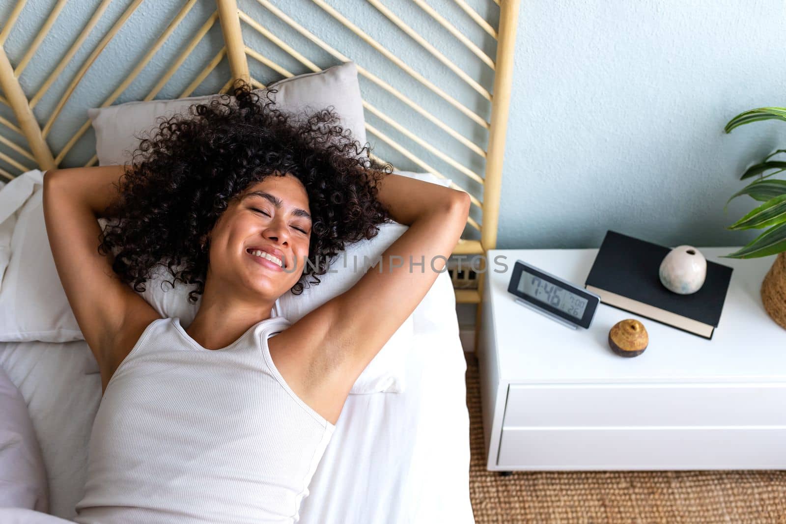 Happy multiracial woman lying down in bed, waking up in the morning. Happiness. Lifestyle concept.