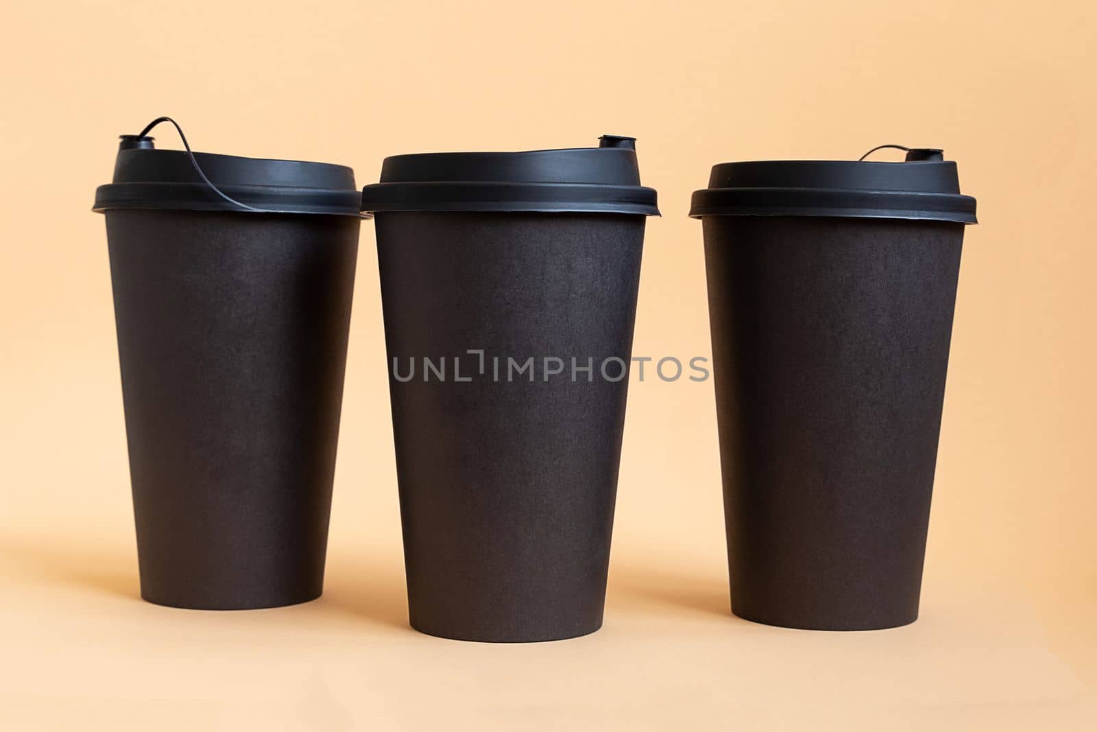 Set of three takeaway black coffee cup on neutral background natural light. Mock -up, nobody, front view by Ri6ka