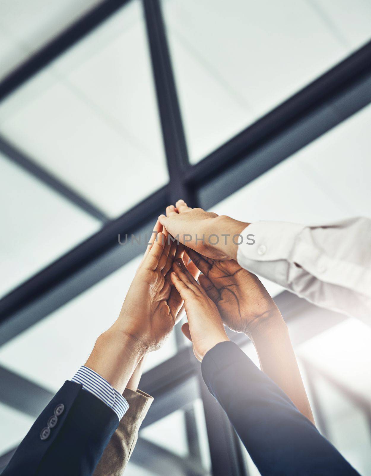 We know that well succeed. a group of businesspeople high-fiving in an office. by YuriArcurs