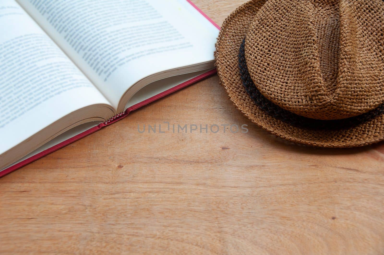 Book and hat on wooden table with customizable space for text or ideas. Copy space.