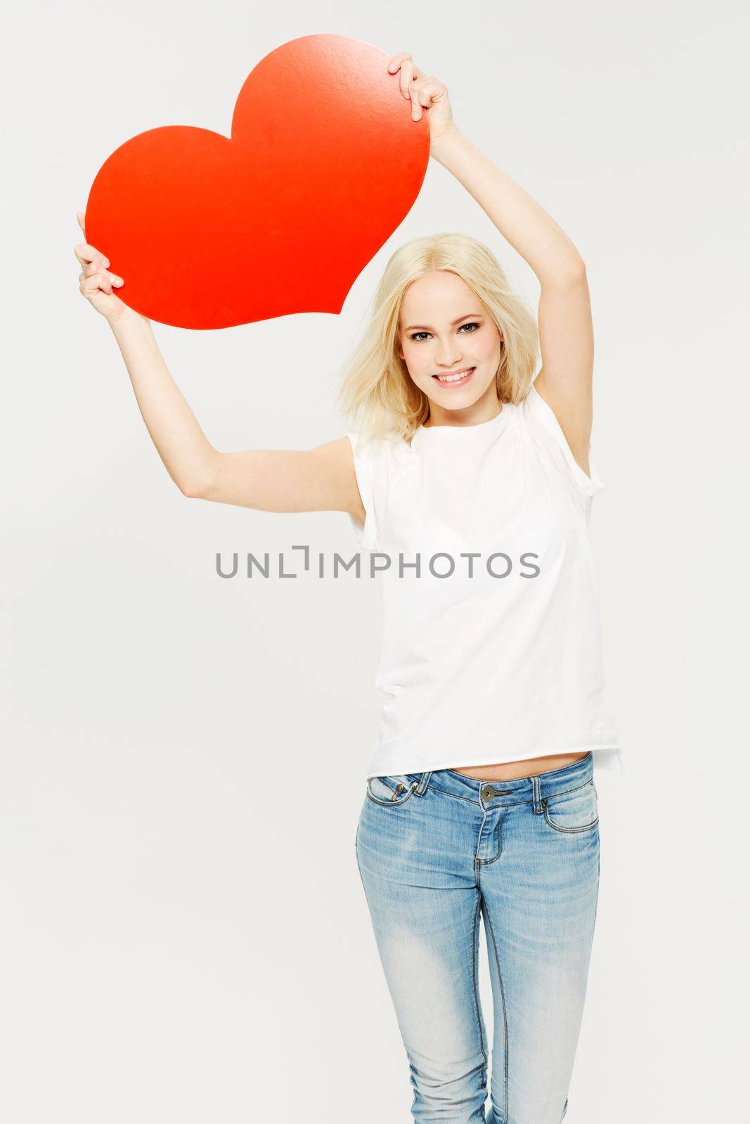 Woman, studio portrait and heart board in hands with happiness, romance and white background. Model, valentines day symbol and isolated with happy, romantic or for dating with cardboard poster sign.